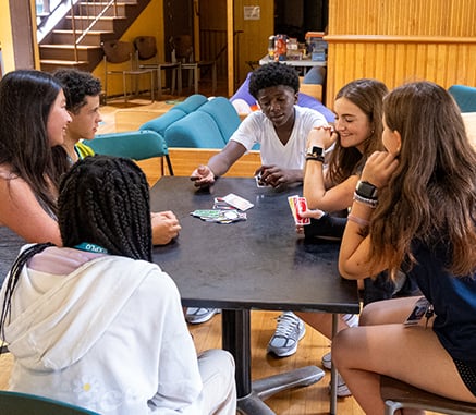 Group of young adults sitting at table playing card game